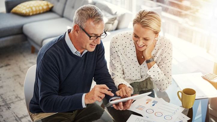 A couple sits together and reviews paperwork on a tablet.